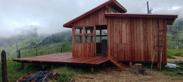 Off-grid tiny wood cabin with deck set in mountain landscape