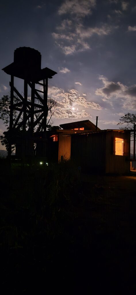 Off-grid tiny cabin at night with moonlight and warm interior light