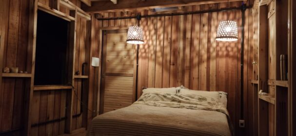 Tiny cabin bedroom interior with wooden walls and warm lighting