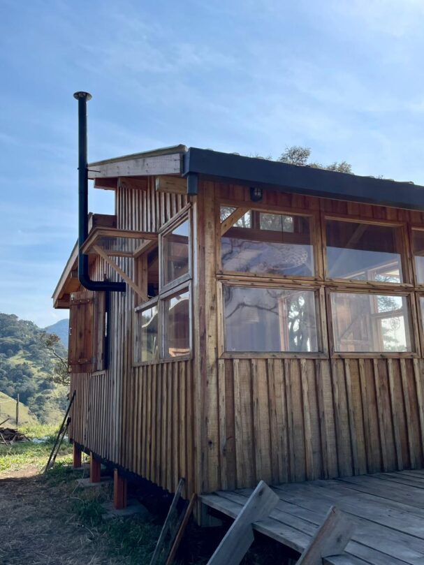 Tiny wood cabin exterior with large windows and wood stove