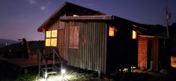 Tiny wood cabin exterior at night with warm interior lights off grid