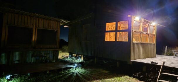 Off-grid tiny wood cabin at night built from Pin-Up Houses plans