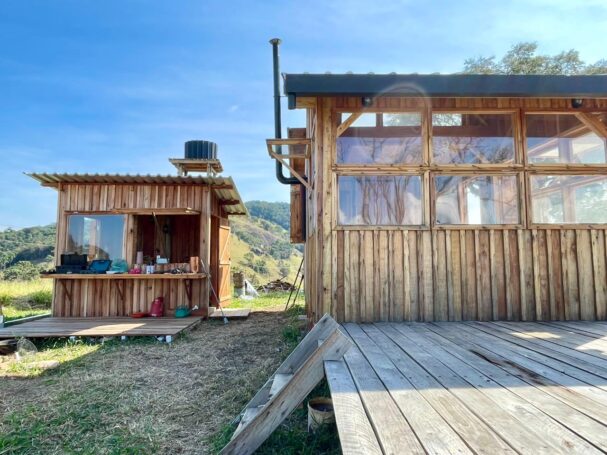 Off-grid tiny wood cabin with auxiliary building and wooden deck